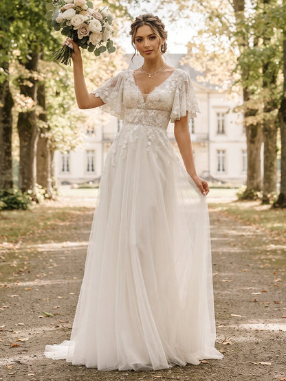 Robe de mariée en tulle, coupe trapèze/princesse, col en V, manches courtes, longueur au sol, avec applications et volants.