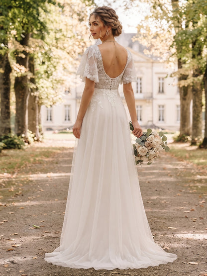 Robe de mariée en tulle, coupe trapèze/princesse, col en V, manches courtes, longueur au sol, avec applications et volants.